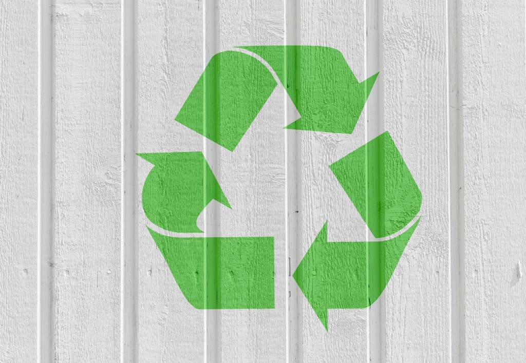 Recycling symbol on white wooden wall background