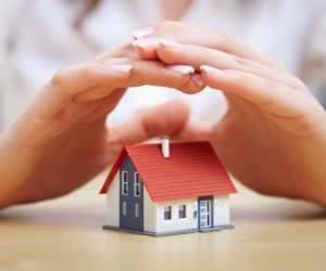 man shielding small house with hands