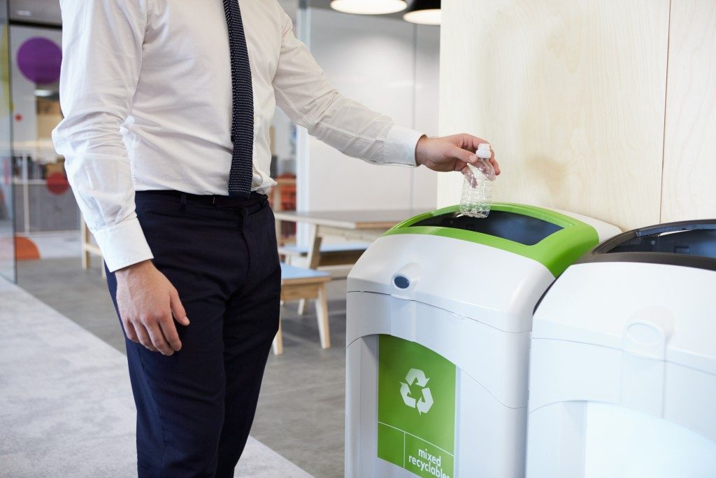 man throwing plastic bottle in recycling bin