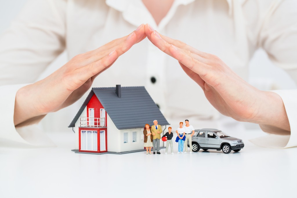 hands over tiny model of house, family and car