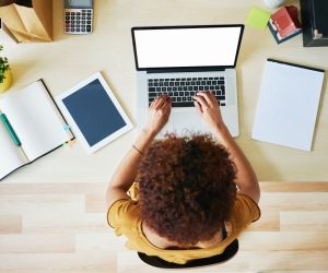 flatlay view of woman working on her laptop along with her note book and tablet