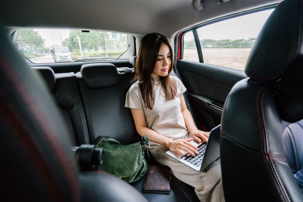 woman working on laptop while riding in a car