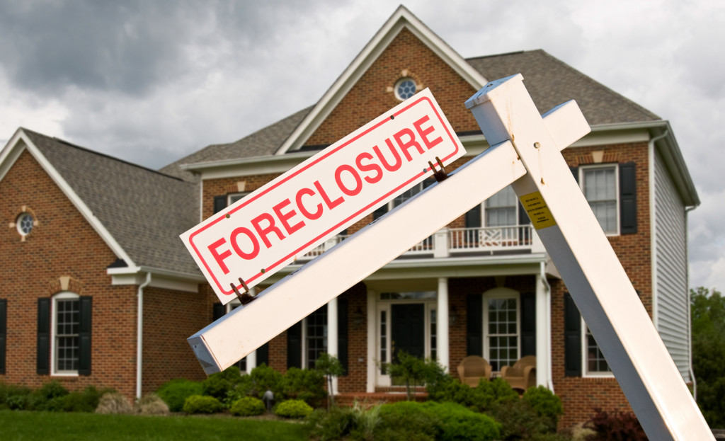 An image of a house with a sign of foreclosure in front of it